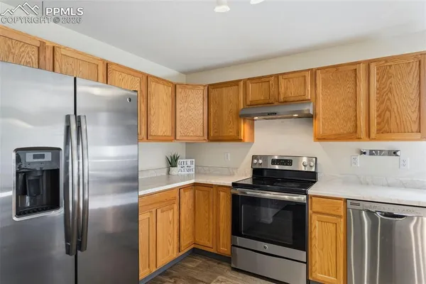 a kitchen with stainless steel appliances granite countertop a refrigerator a sink and a stove