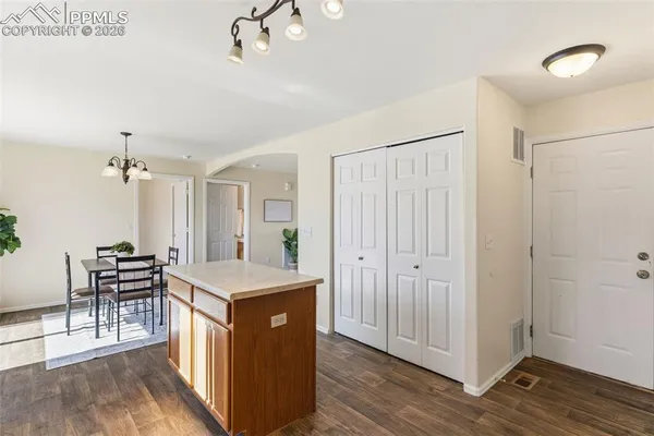 a hall with kitchen island white cabinets and wooden floor