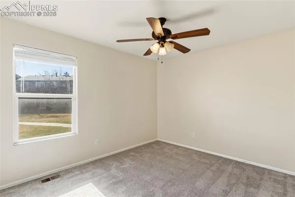 an empty room with a window and a fan