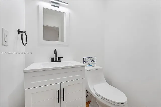 a bathroom with a toilet sink vanity and mirror