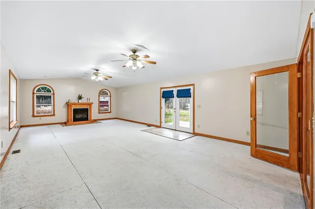 a view of an empty room with chandelier fan and window