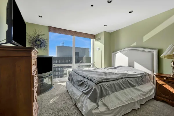 a bedroom with a bed and flat tv screen on wall