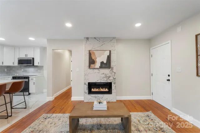 a living room with stainless steel appliances furniture a rug and a fireplace