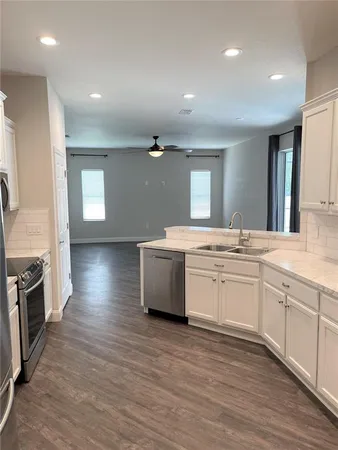 a large kitchen with a sink and dishwasher a stove top oven with wooden floor