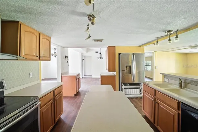 a large kitchen with stainless steel appliances a stove a sink dishwasher and wooden cabinets with wooden floor