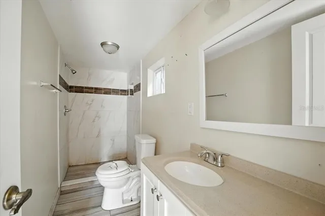 a bathroom with a granite countertop sink toilet a mirror and shower