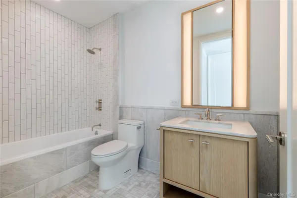 a bathroom with a granite countertop sink toilet a large mirror a bathtub and shower