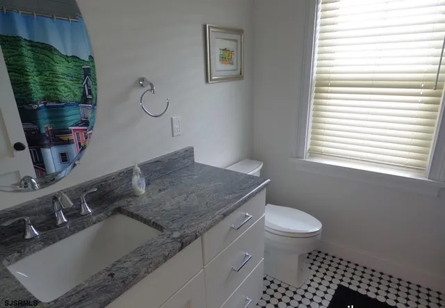 a bathroom with a granite countertop sink a toilet and a mirror