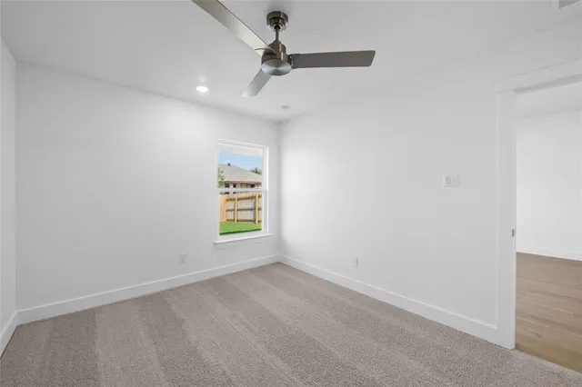 an empty room with a window and a ceiling fan