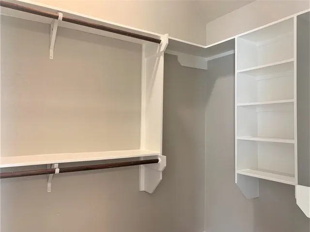 a view of an empty room with window and chandelier fan