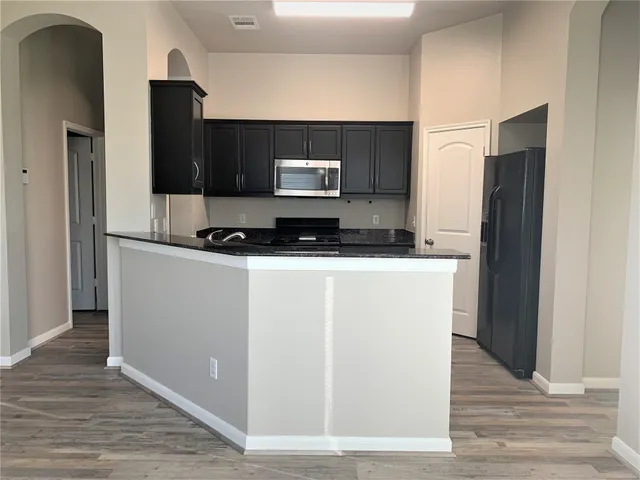 a kitchen with granite countertop a refrigerator and a stove top oven