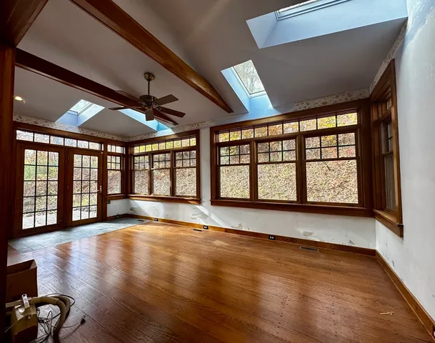 a view of an empty room with wooden floor and a window