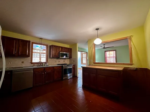 a large kitchen with granite countertop a stove top oven a sink dishwasher a dining table and chairs with wooden floor