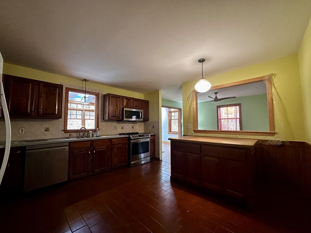 46 Swan Point Road Rindge, NH 03461 - Photo 14 of 42 a large kitchen with granite countertop a stove top oven a sink dishwasher a dining table and chairs with wooden floor