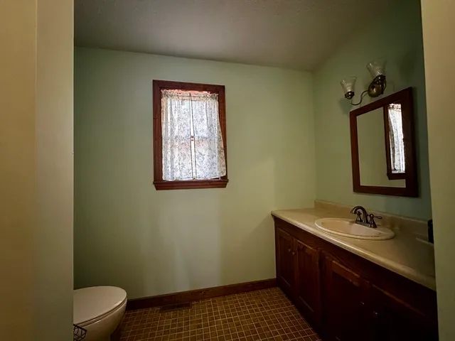 a bathroom with a sink a toilet a window and vanity