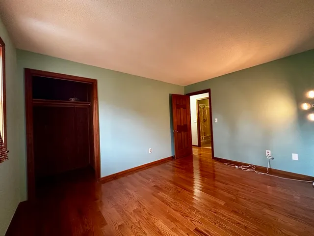a view of an empty room with wooden floor and closet