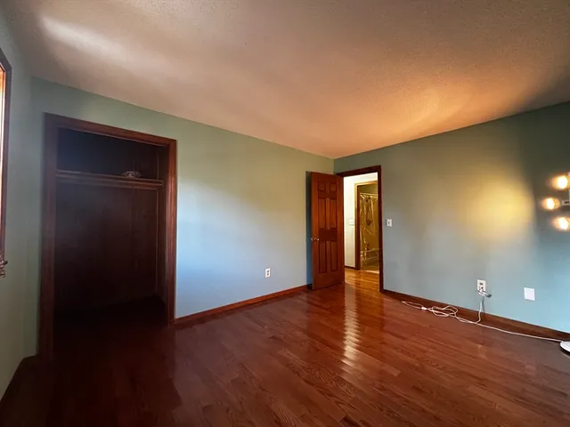 a view of an empty room with wooden floor and closet