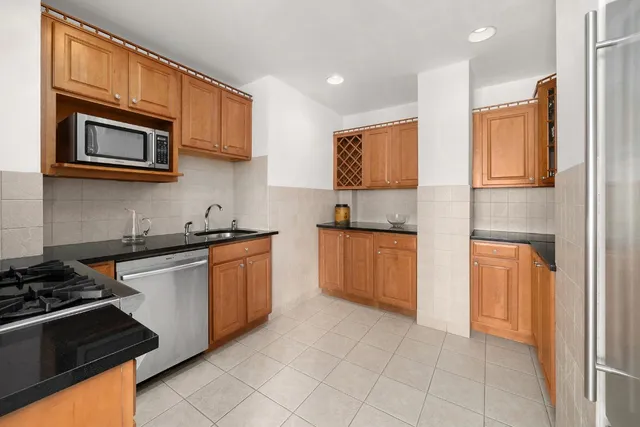a kitchen with stainless steel appliances granite countertop a stove top oven a sink dishwasher and a refrigerator