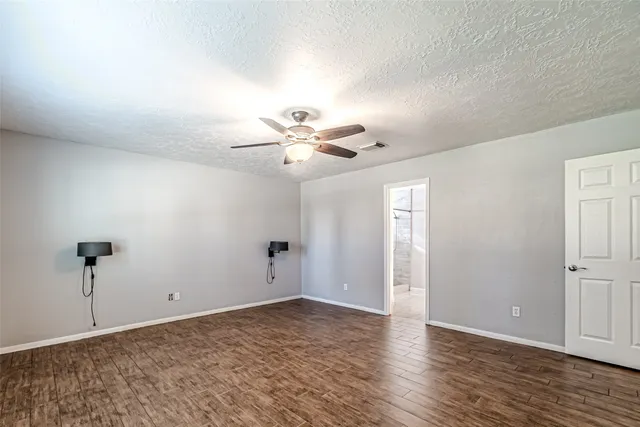 an empty room with windows and ceiling fan