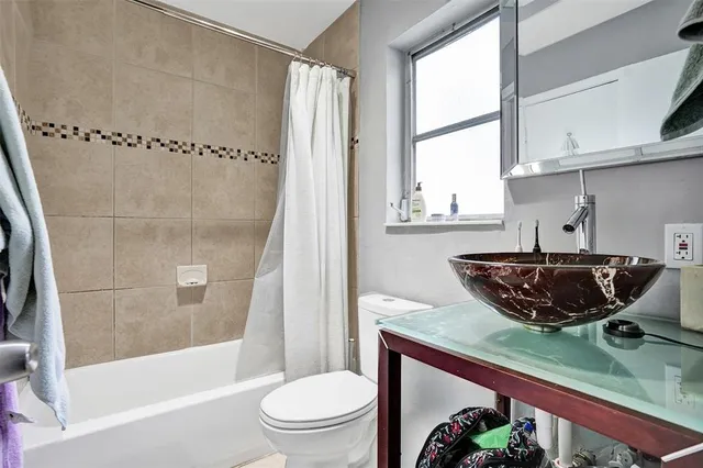 a bathroom with a granite countertop bathtub shower sink vanity and toilet