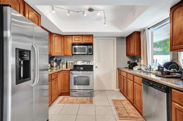 a kitchen with stainless steel appliances granite countertop a stove top oven a sink dishwasher a refrigerator and cabinets with wooden floor