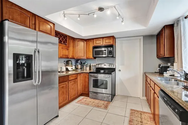 a kitchen with stainless steel appliances granite countertop a refrigerator a sink dishwasher a stove with wooden cabinets