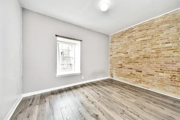 an empty room with wooden floor and window