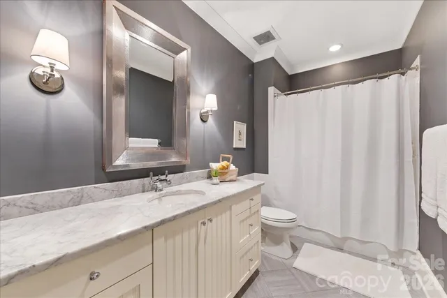 a bathroom with a granite countertop sink and a toilet