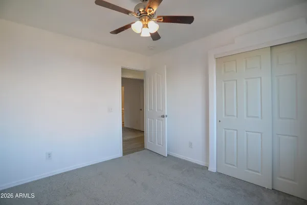 an empty room with closet and a chandelier fan