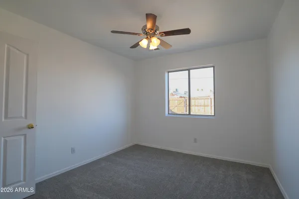 an empty room with a window and a chandelier fan