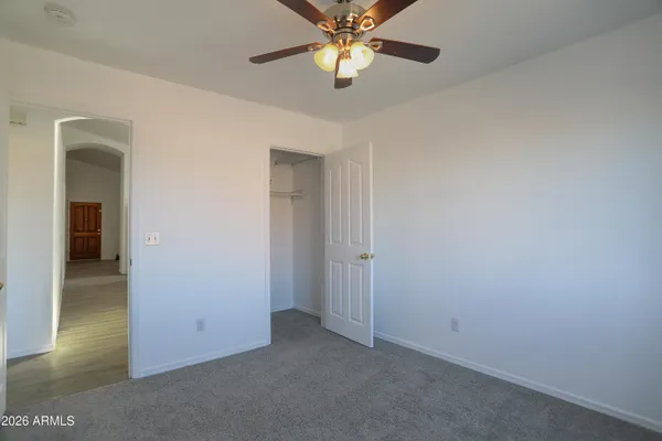 an empty room with closet and a chandelier fan