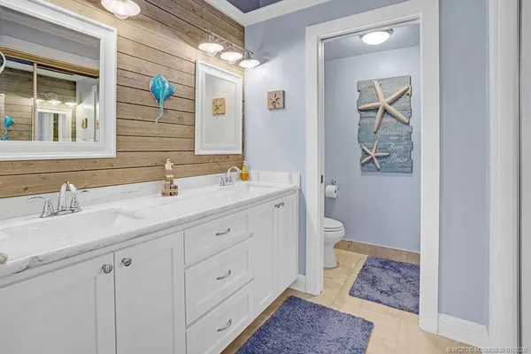 a bathroom with a double vanity sink and mirror with toilet