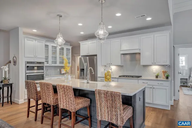 a kitchen with stainless steel appliances granite countertop a kitchen island a stove a table and chairs
