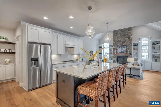 a kitchen with stainless steel appliances granite countertop a refrigerator a stove a sink a dining table and chairs with wooden floor