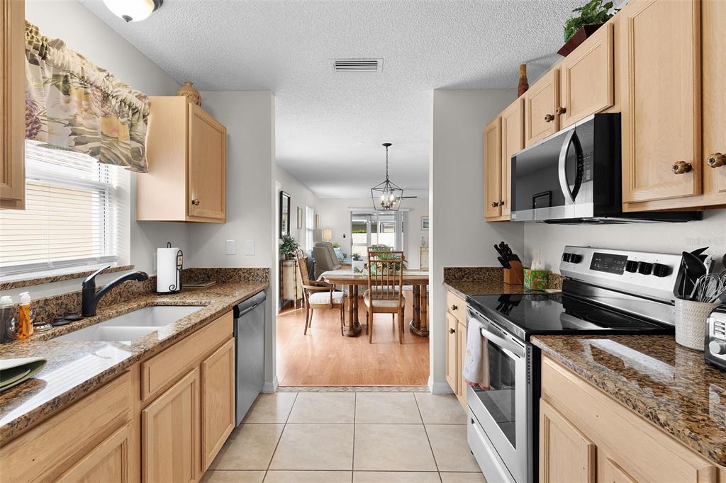 1116 San Bernardo Road The Villages, FL 32162 - Photo 19 of 46 a kitchen with stainless steel appliances granite countertop a stove a sink and a microwave