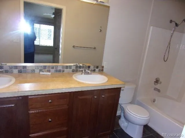 a bathroom with a granite countertop sink toilet and shower
