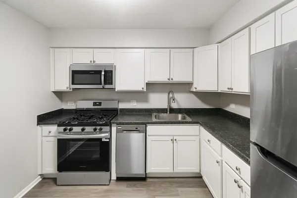 a kitchen with granite countertop a stove top oven microwave and cabinets