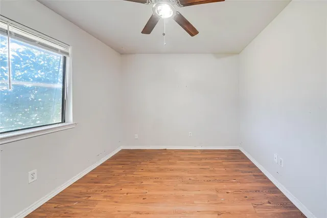 a view of empty room with wooden floor and fan