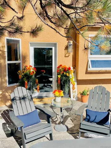 a view of a patio with table and chairs potted plants and a large tree
