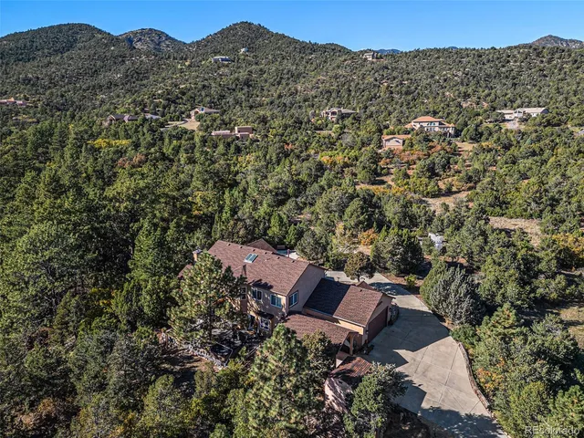 an aerial view of a house with a yard and mountain view in back