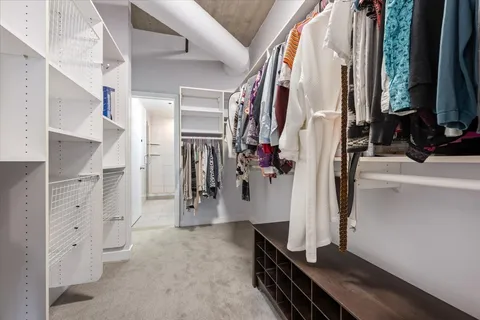 a view of walk in closet with clothes and shoes