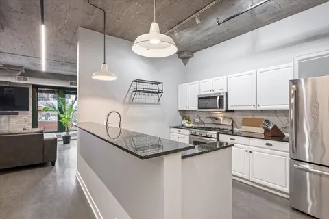 a kitchen with stainless steel appliances granite countertop a sink a stove a refrigerator cabinets and chairs