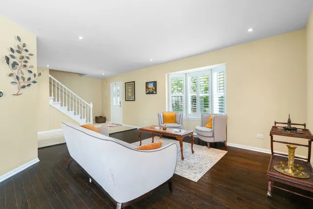a living room with couches chairs and wooden floor next to a window