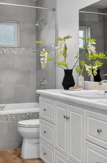 a bathroom with a granite countertop sink a toilet a mirror and shower
