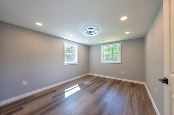 an empty room with wooden floor and windows