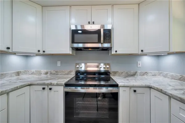 a kitchen with granite countertop white cabinets and a stove