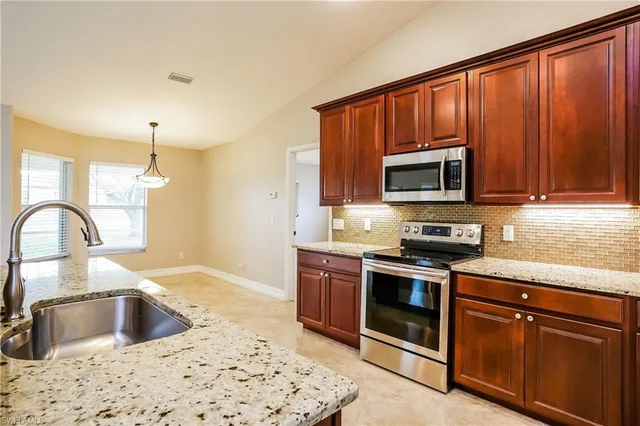 a kitchen with granite countertop a stove a sink and a microwave