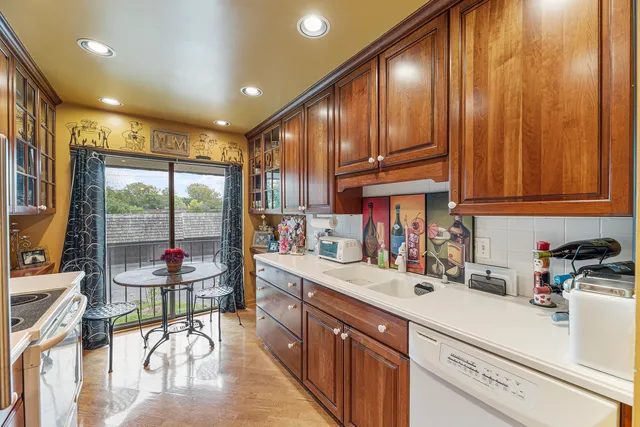 a kitchen with stainless steel appliances kitchen island granite countertop a refrigerator a sink a dining table and chairs with wooden floor