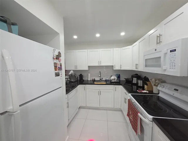 a kitchen with granite countertop a sink and white cabinets