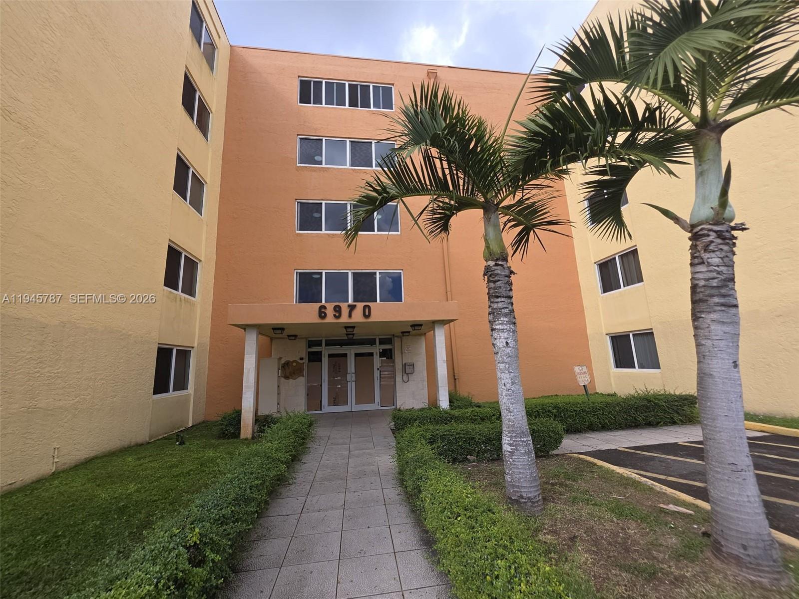 6970 Northwest 186th Street, Unit 3307 Hialeah, FL 33015 - Photo 17 of 21 a front view of a multi story residential apartment building with yard and entryway